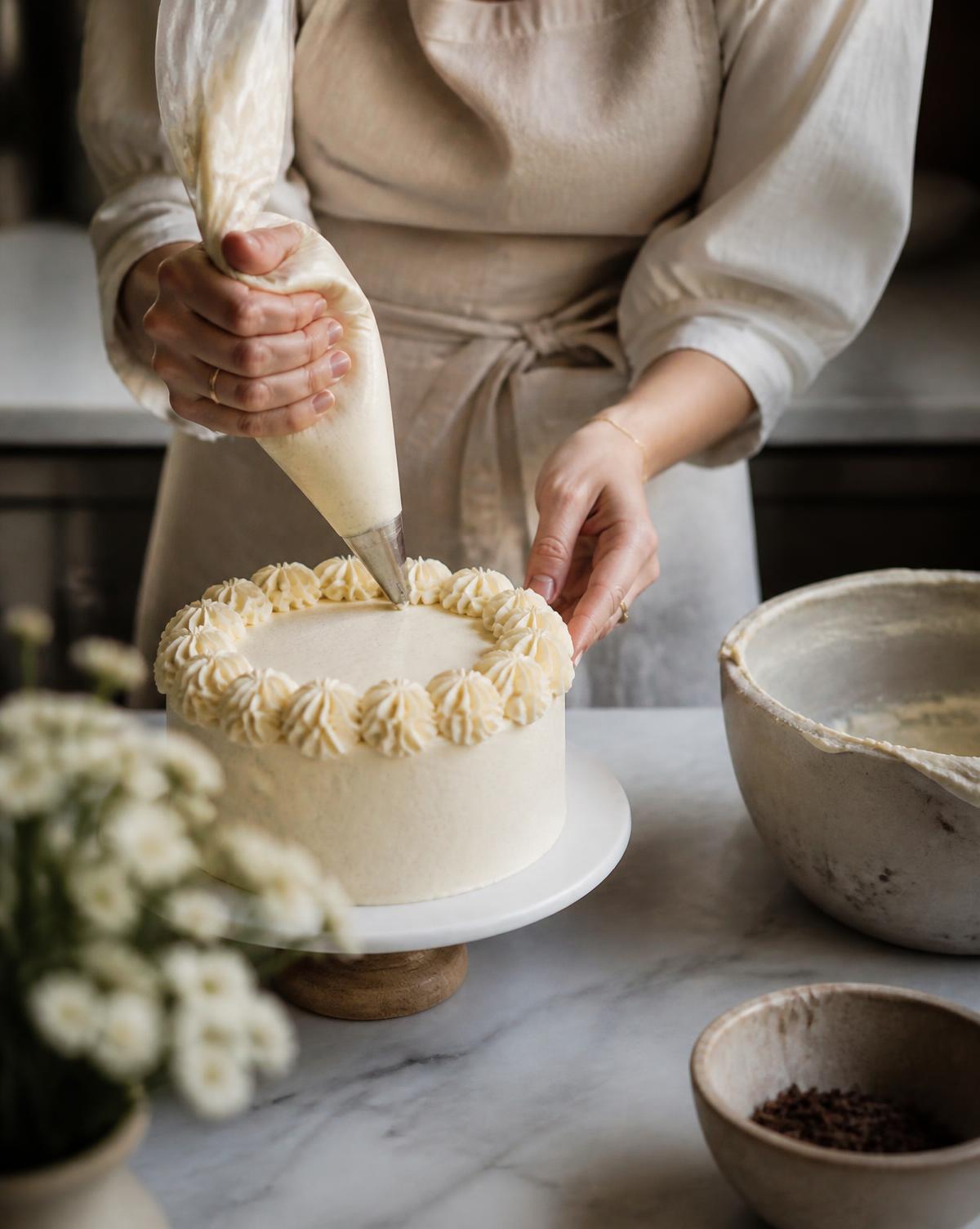 Pastry chef piping cream onto a cake